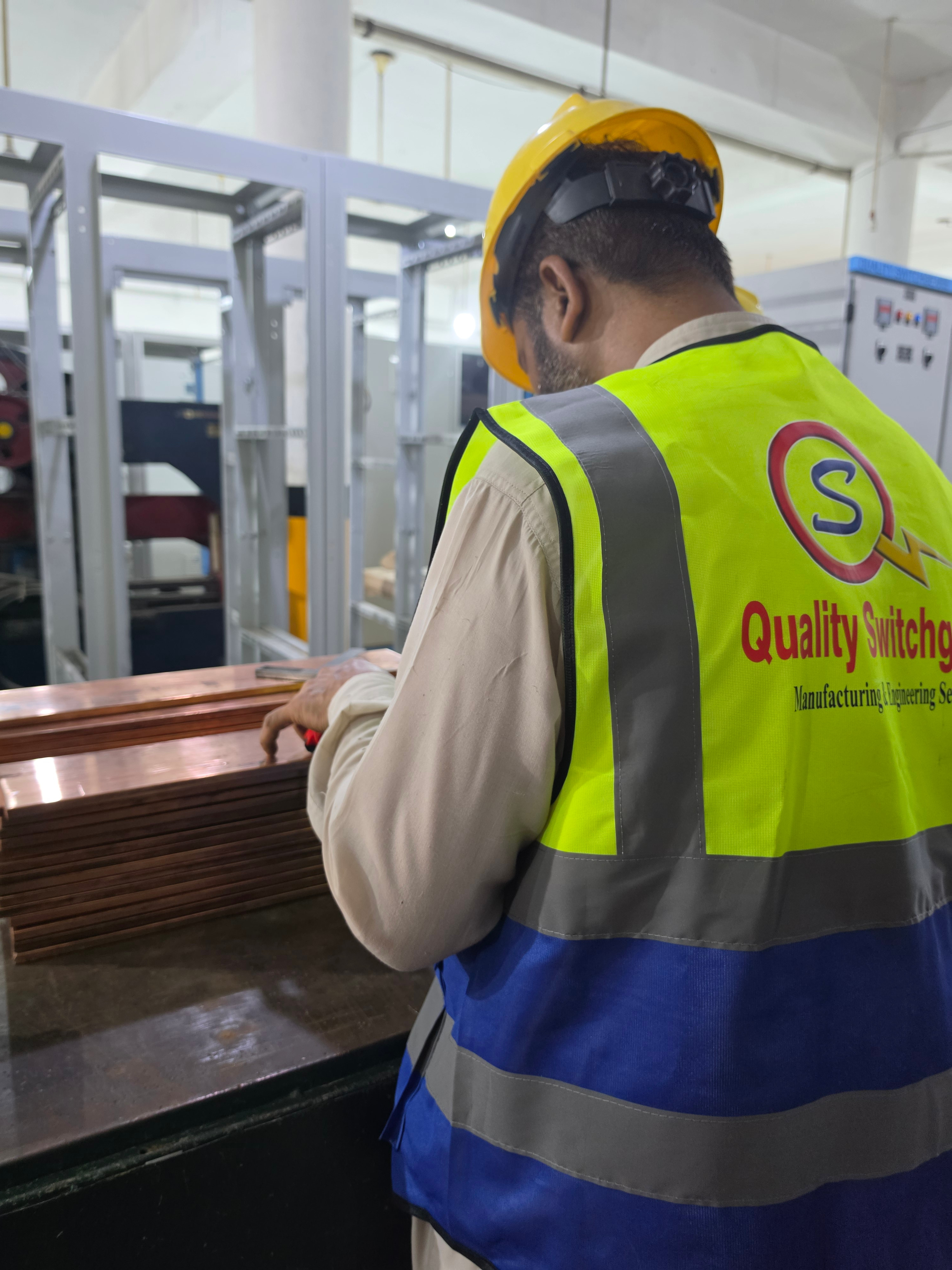 Copper busbar stock measured on the Quality Switchgears fabrication bench.